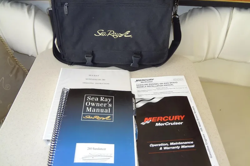 Slide: The Image of Sea Ray Sundancer 280 manuals and bag, 2002 model, displayed on a table. - 40
