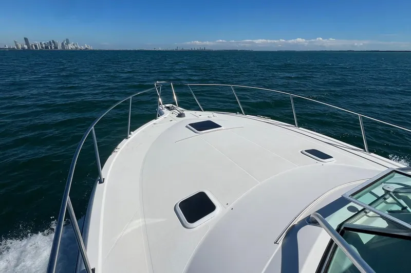 Slide: The Image of 2005 Rampage 38 Express yacht cruising on open sea with city skyline in background. - 1