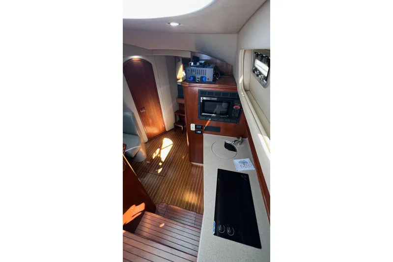 Slide: The Image of Interior of 2005 Rampage 38 Express yacht, featuring a compact kitchen and wooden flooring. - 18