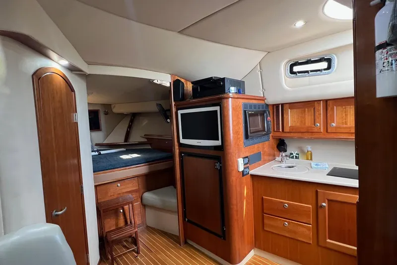 Slide: The Image of 2005 Rampage 38 Express yacht interior with kitchenette, wood cabinetry, and cozy sleeping area. - 21