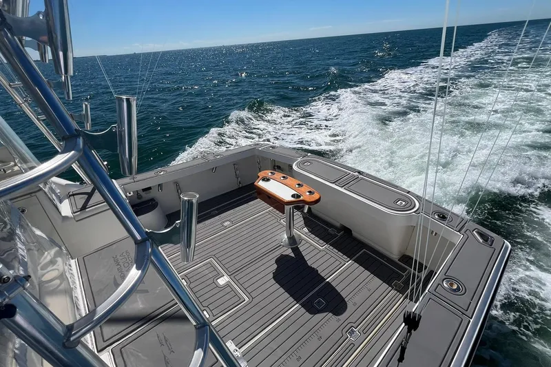 Slide: The Image of 2005 Rampage 38 Express boat cruising on open sea, featuring spacious deck and fishing equipment. - 7