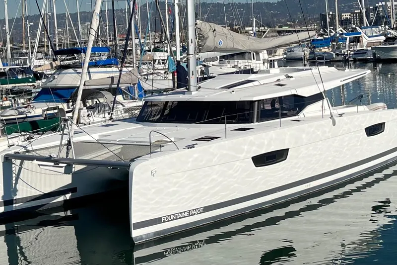 Slide: The Image of 2018 Fountaine Pajot Saona catamaran docked in a marina, surrounded by other boats. - 1