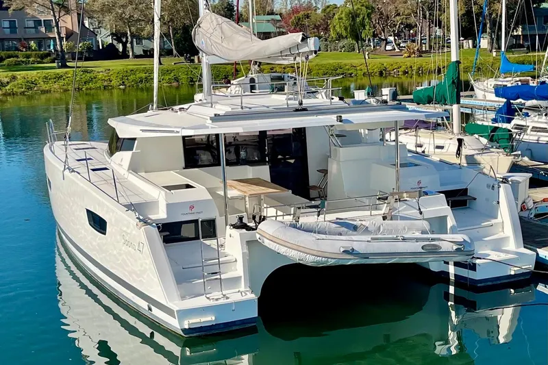 Slide: The Image of 2018 Fountaine Pajot Saona catamaran docked in a serene marina setting. - 2
