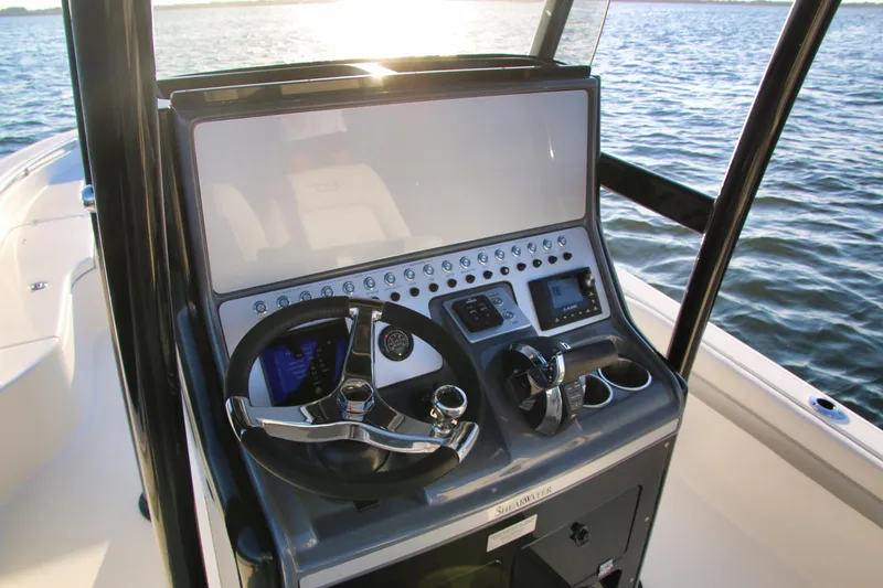 Slide: The Image of 2023 ShearWater 260 SS Carolina boat console with steering wheel and controls on water. - 15