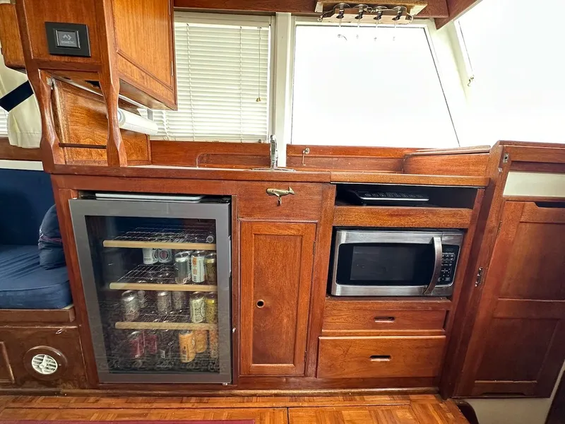 Slide: The Image of 1974 Grand Banks 32 Sedan interior with wooden cabinetry, mini fridge, and microwave. - 26