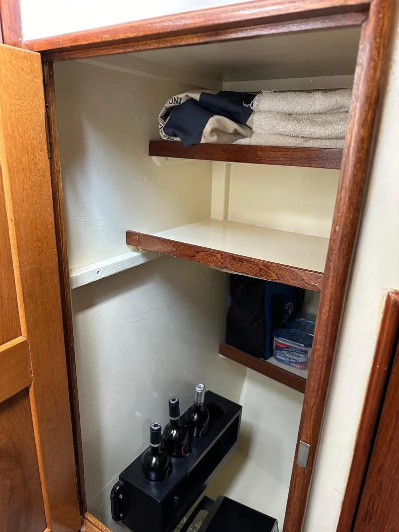 Slide: The Image of 1974 Grand Banks 32 Sedan interior closet with shelves, towels, and wine bottles. - 27