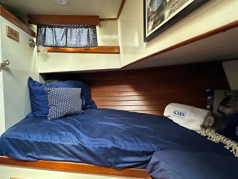 Slide: The Image of 1974 Grand Banks 32 Sedan cabin with cozy bed, blue bedding, and wooden accents. - 30