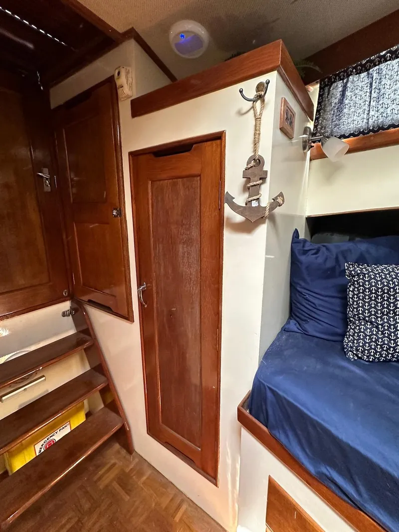 Slide: The Image of 1974 Grand Banks 32 Sedan interior with wooden cabinetry and blue bedding. - 34