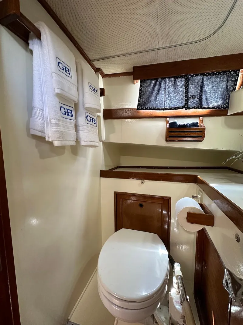 Slide: The Image of 1974 Grand Banks 32 Sedan bathroom with towels, toilet, and wooden accents. - 38