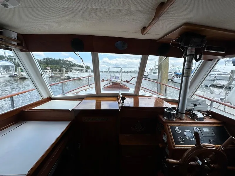 Slide: The Image of 1974 Grand Banks 32 Sedan interior view, showcasing helm and marina through windows. - 45