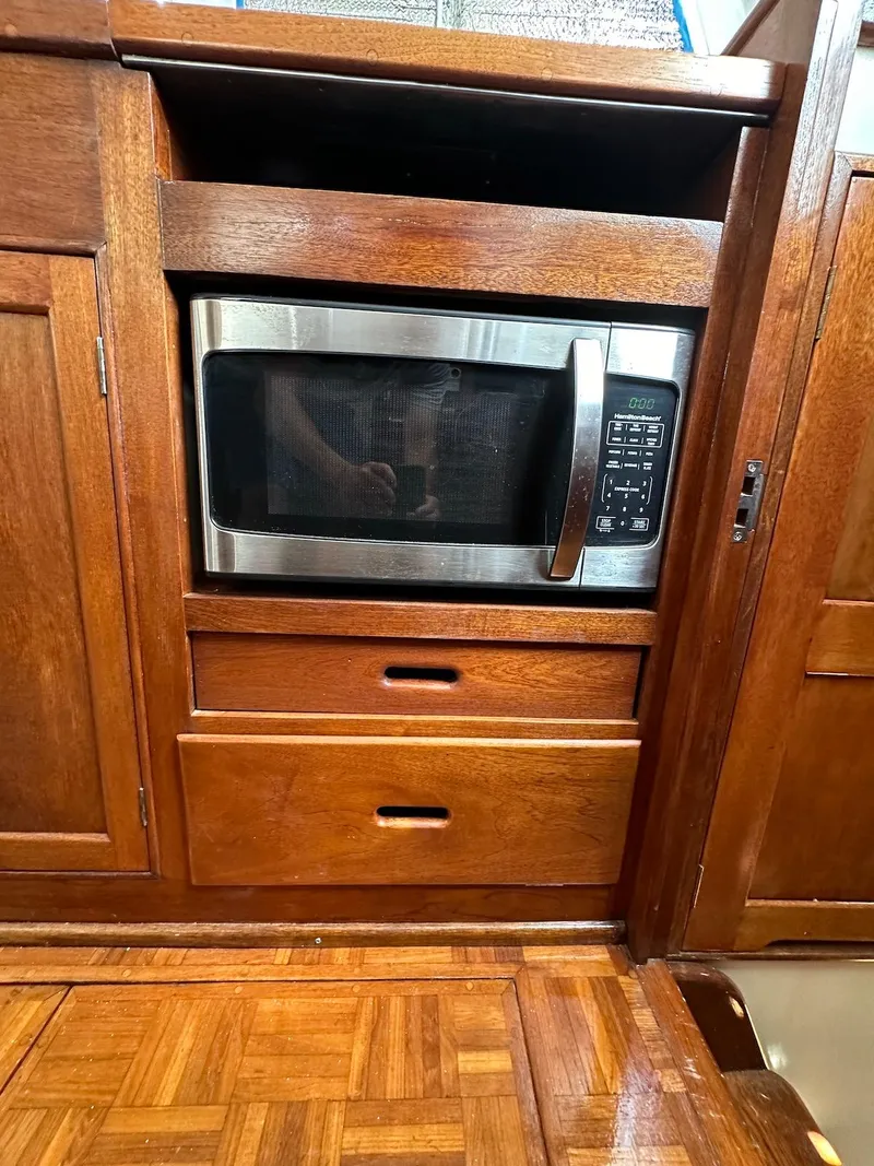 Slide: The Image of 1974 Grand Banks 32 Sedan interior with built-in microwave and wooden cabinetry. - 49
