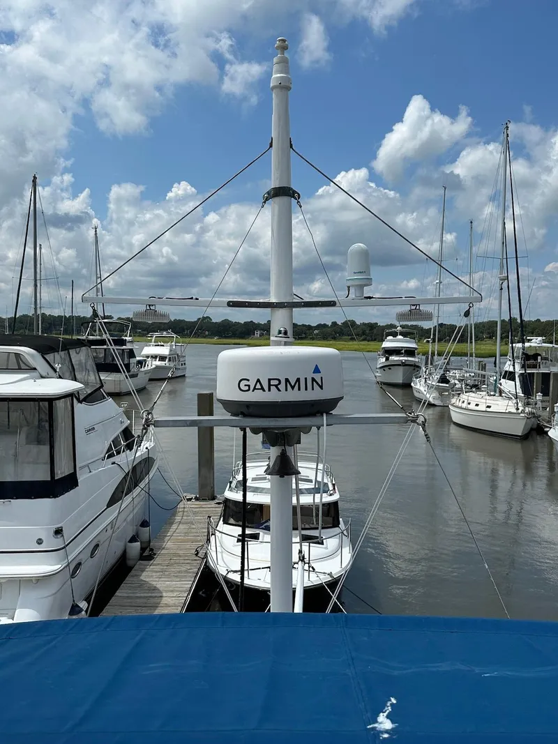 Slide: The Image of 1974 Grand Banks 32 Sedan docked, featuring Garmin equipment, surrounded by other boats under a cloudy sky. - 9