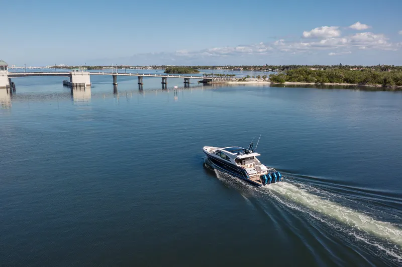 Slide: The Image of 2022 Formula 500 Super Sport Crossover cruising on a serene waterway near a bridge. - 11