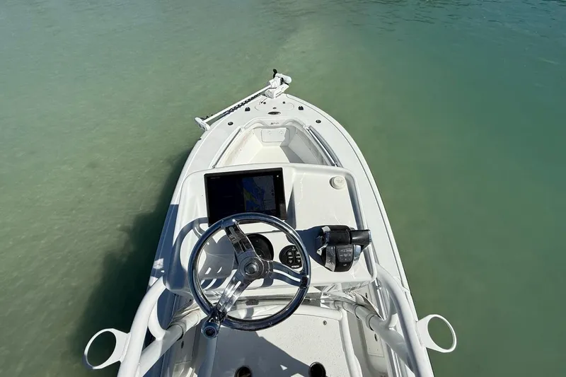 Slide: The Image of 2017 Yellowfin 26 Hybrid boat dashboard with steering wheel and controls on calm water. - 12