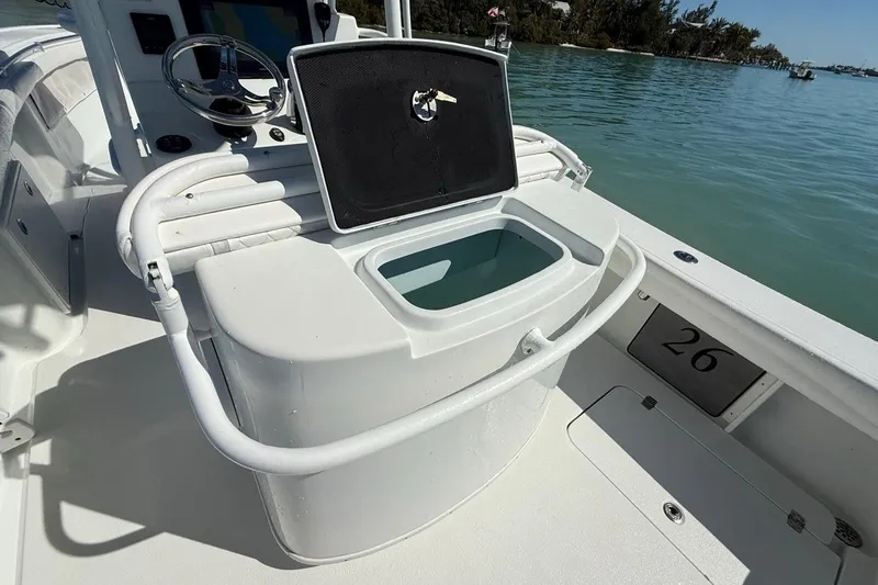 Slide: The Image of 2017 Yellowfin 26 Hybrid boat interior with open storage compartment, steering wheel, and water view. - 24