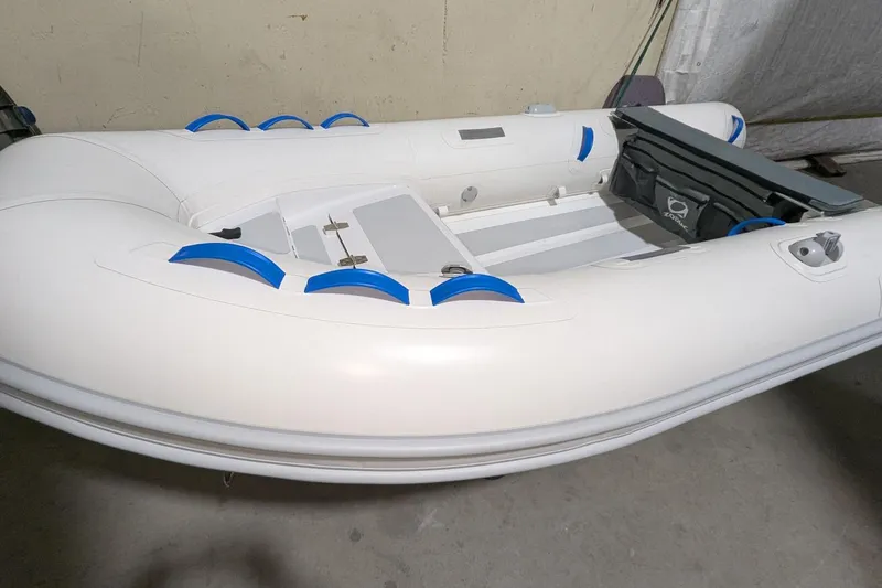 The Image of 2025 Zodiac Nomad 3.3 RIB Alu inflatable boat with blue accents, displayed indoors. - 1