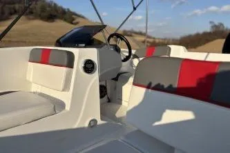 Slide: The Image of 2023 Tahoe T16 boat interior with red and gray seating, steering wheel, and dashboard. - 11