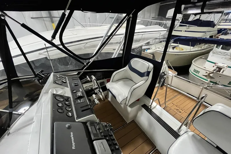 Slide: The Image of 1995 Carver 325 Aft Cabin Motor Yacht helm with controls and seating in marina. - 8