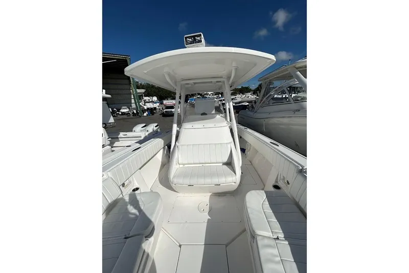 Slide: The Image of 2014 Intrepid 327 Center Console boat with white seating and canopy, docked under clear skies. - 10