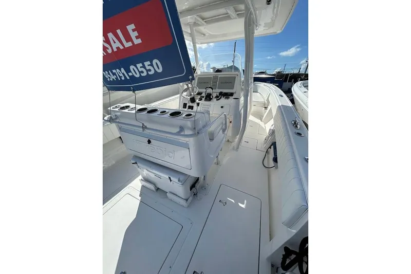 Slide: The Image of 2014 Intrepid 327 Center Console boat interior with sale sign, featuring helm and seating area. - 14