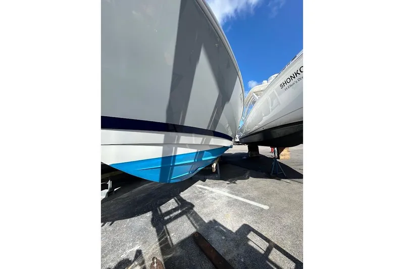 Slide: The Image of 2014 Intrepid 327 Center Console boat on dry dock, blue hull, sunny day. - 16