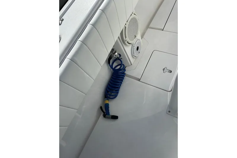 Slide: The Image of 2014 Intrepid 327 Center Console boat deck with coiled blue hose and speaker. - 8