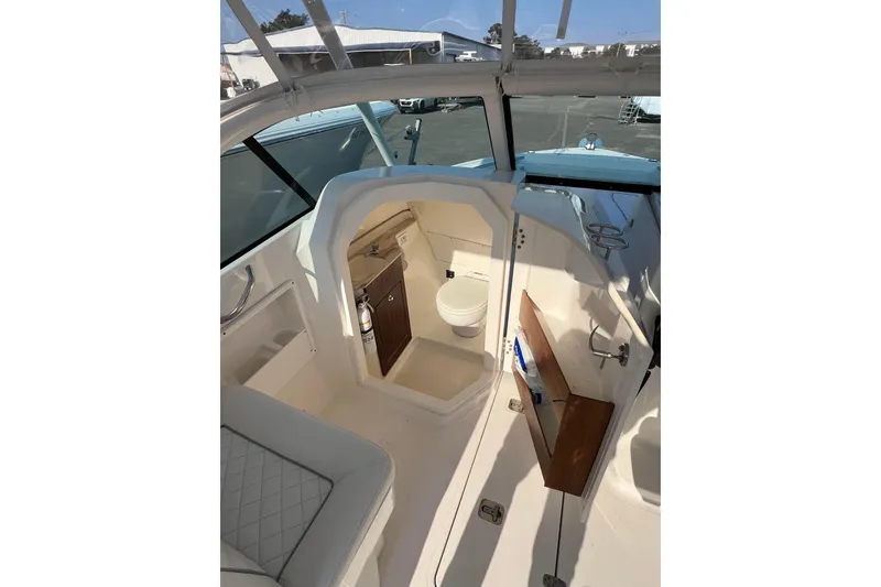 Slide: The Image of 2024 Pursuit DC 246 Dual Console boat interior with compact bathroom and seating area. - 12