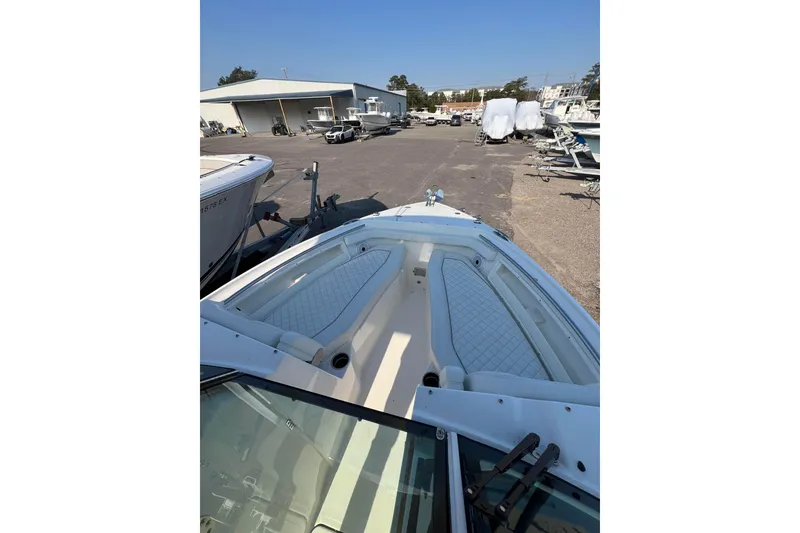 Slide: The Image of 2024 Pursuit DC 246 Dual Console boat with spacious seating, docked in a marina. - 13