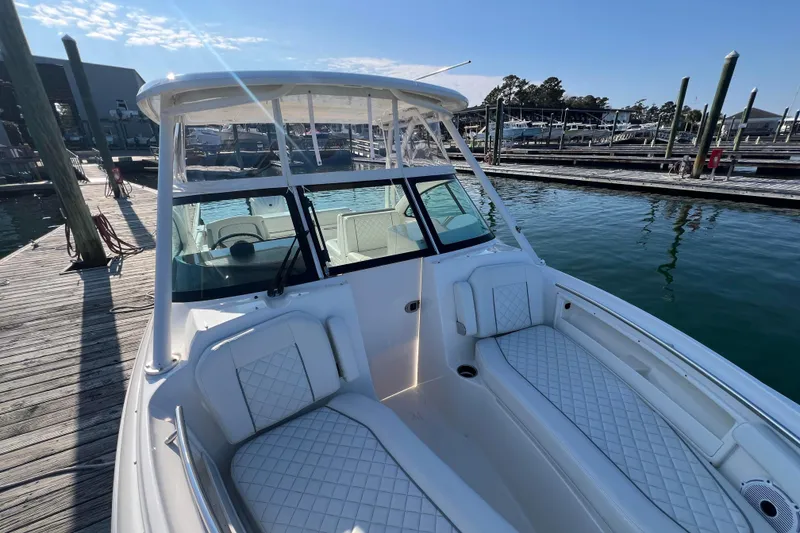 Slide: The Image of 2024 Pursuit DC 246 Dual Console boat docked at marina under clear sky. - 3