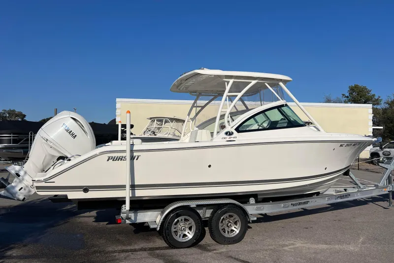 Slide: The Image of 2024 Pursuit DC 246 Dual Console boat on trailer, side view, clear sky background. - 7