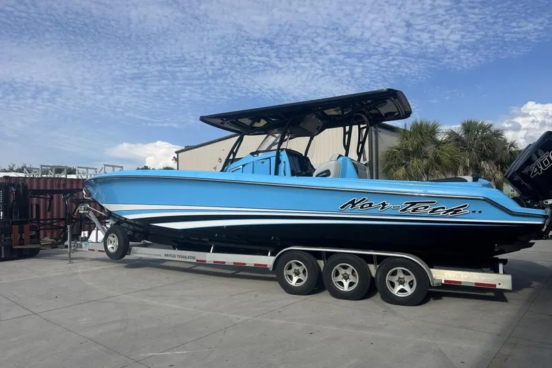 The Image of 2025 Nor-Tech 340 Sport Center Console boat on trailer, blue exterior, parked outdoors. - 0