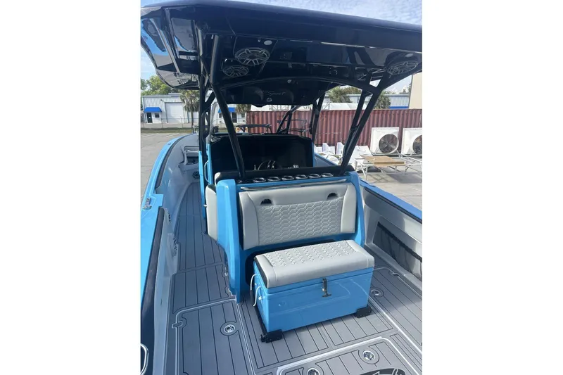 Slide: The Image of 2025 Nor-Tech 340 Sport Center Console boat with blue and gray seating, docked outdoors. - 21