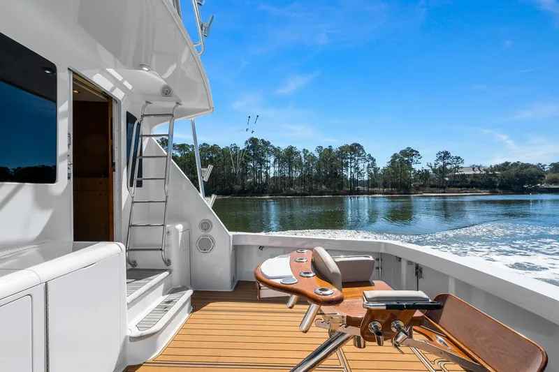 Slide: The Image of 2002 Viking 61 Convertible yacht deck with fishing chair, overlooking serene water and trees. - 10