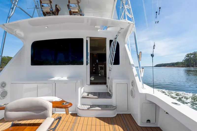 Slide: The Image of 2002 Viking 61 Convertible yacht deck with seating, overlooking serene water and clear sky. - 11