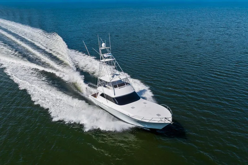 Slide: The Image of 2002 Viking 61 Convertible yacht cruising on open water, creating a wake. - 5