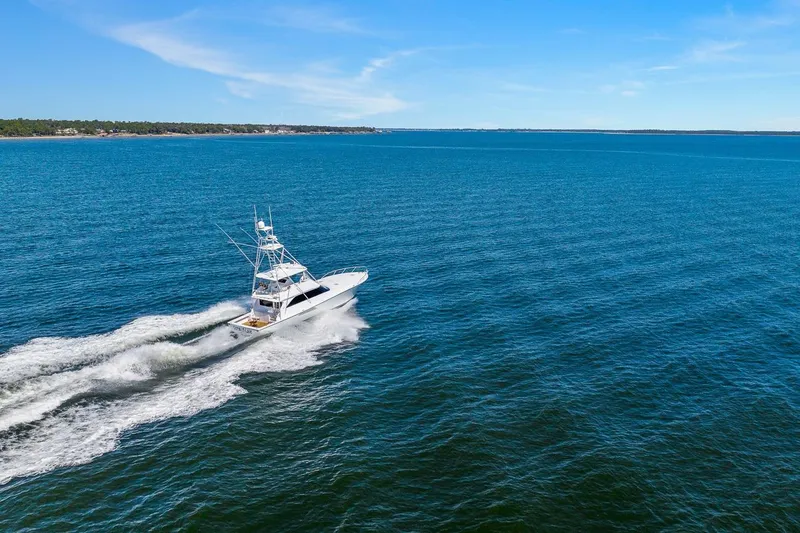 Slide: The Image of 2002 Viking 61 Convertible yacht cruising on open blue sea under clear sky. - 64