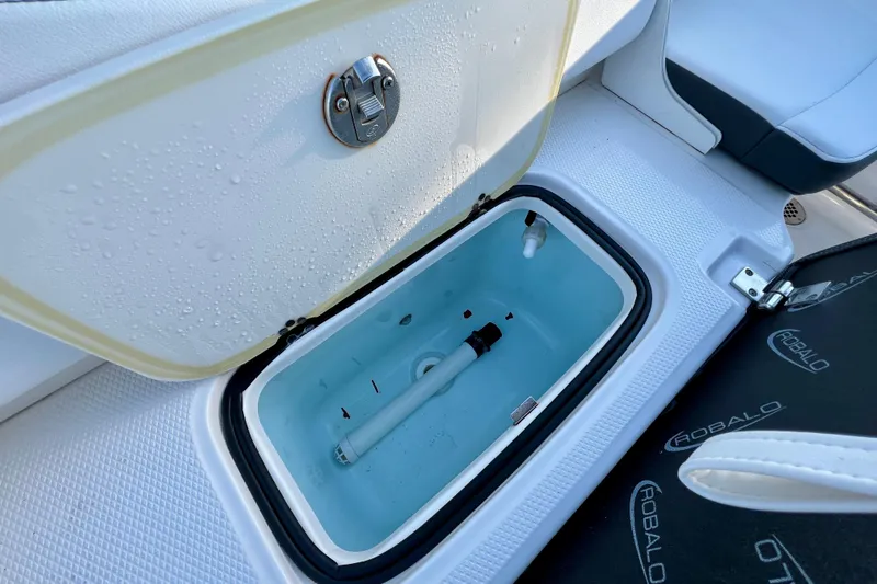 Slide: The Image of 2024 Robalo R207 Dual Console boat storage compartment with open lid and visible interior. - 9