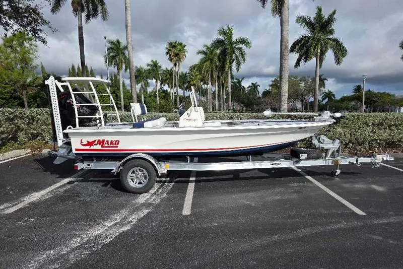 Slide: The Image of 2026 Mako 18 Pro Skiff Patriot Edition on trailer, parked with palm trees in background. - 94