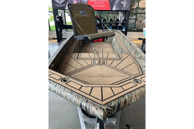 Slide: The Image of 2026 Tracker Grizzly 1650 T Prairie Wings Edition boat with camouflage design in showroom. - 3