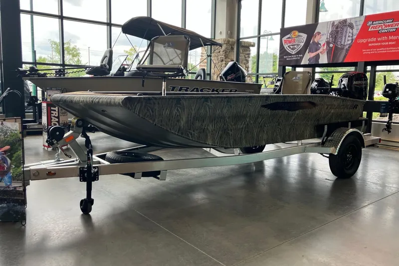 Slide: The Image of 2026 Tracker Grizzly 1650 T Prairie Wings Edition boat displayed in showroom on trailer. - 2