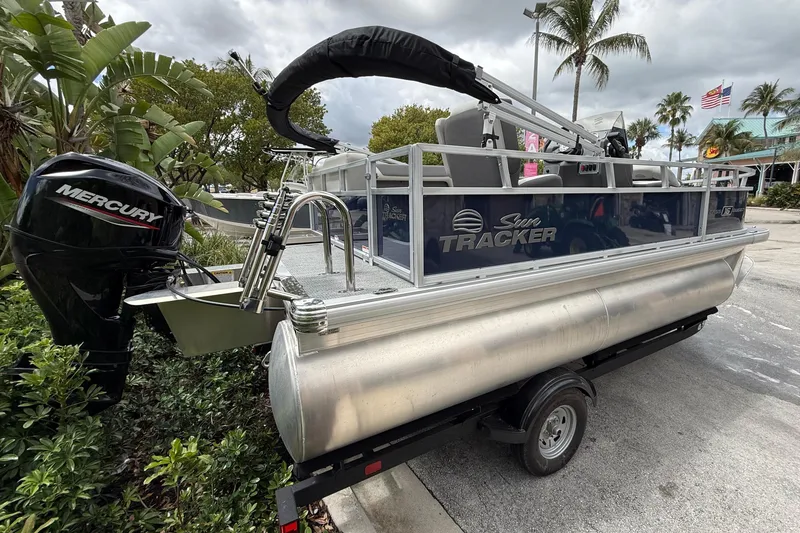 Slide: The Image of 2026 Sun Tracker Bass Buggy 16 XL Select pontoon boat with Mercury engine on trailer. - 2