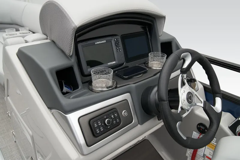 Slide: The Image of 2026 Regency 230 DL boat dashboard with steering wheel, navigation system, and cup holders. - 11