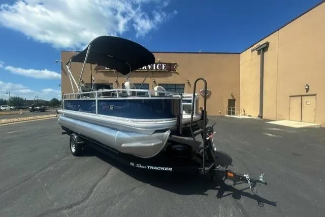 The Image of 2026 Sun Tracker Bass Buggy 18 DLX pontoon boat on trailer, parked outdoors. - 0