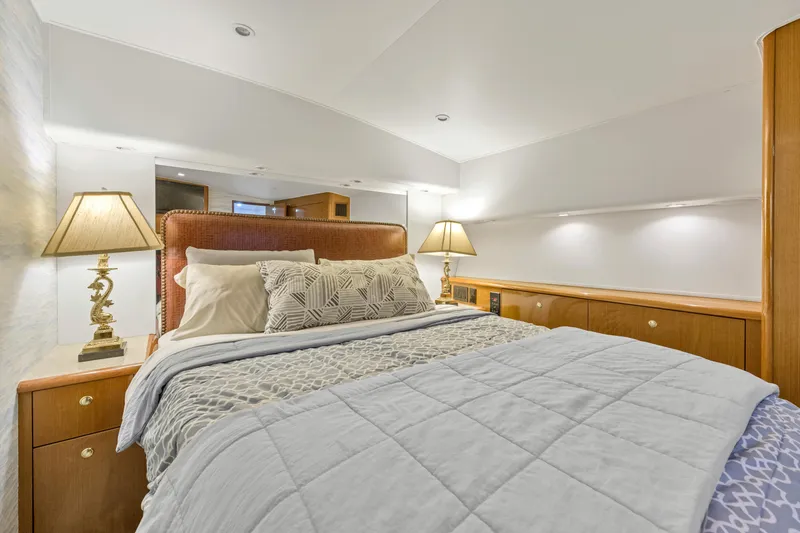 Slide: The Image of Luxurious bedroom interior of a 2001 Viking 55 Convertible yacht with elegant bedding and lamps. - 21