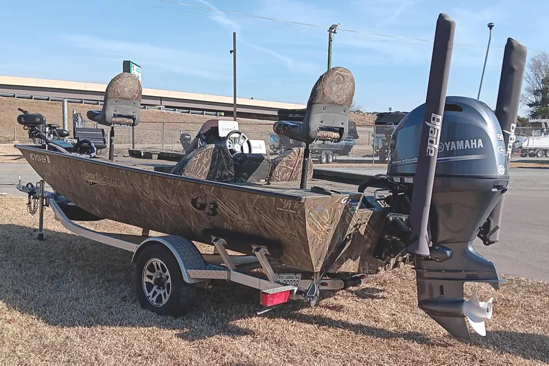 Slide: The Image of 2018 G3 Sportsman 17 Camo boat with Yamaha motor on trailer, parked outdoors. - 4