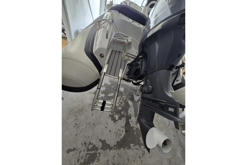 Slide: The Image of 2025 Walker Bay Venture 13 boat with motor and ladder, docked indoors. - 10