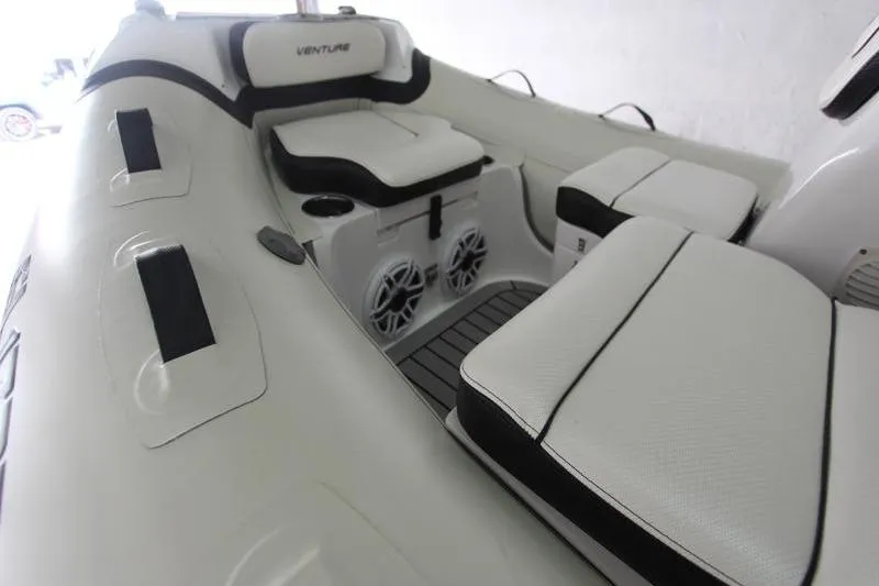 Slide: The Image of 2025 Walker Bay Venture 13 boat interior with cushioned seating and built-in speakers. - 13