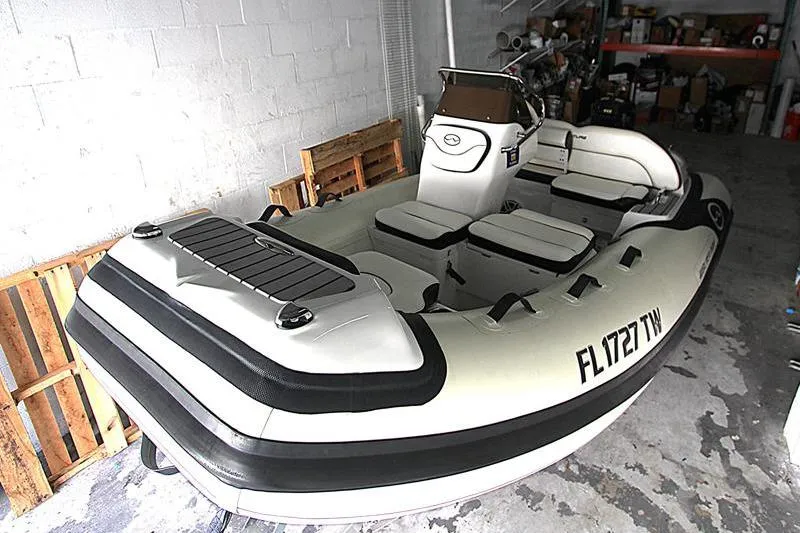 Slide: The Image of 2025 Walker Bay Venture 13 inflatable boat in a storage area, featuring cushioned seating. - 17