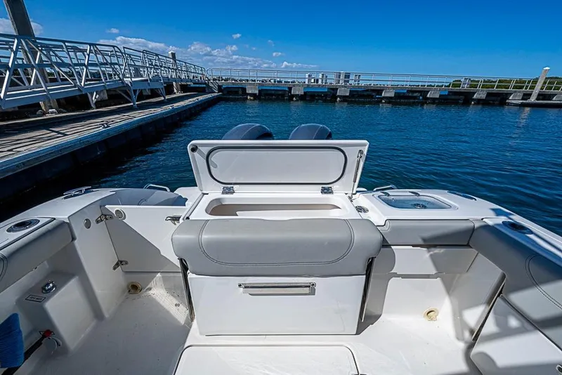 Slide: The Image of 2022 Pursuit DC 266 Dual Console boat interior at marina, featuring open storage compartment. - 15