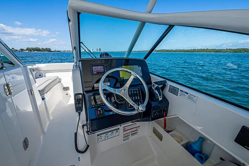 Slide: The Image of 2022 Pursuit DC 266 Dual Console boat interior with steering wheel and ocean view. - 2
